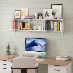 a computer monitor sitting on top of a desk next to a white book shelf filled with books