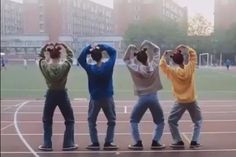 four people standing on a basketball court with their hands in the air and one person holding his head