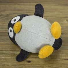 a stuffed penguin is sitting on a wooden floor with its eyes open and tongue out