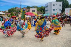 colorfully dressed dancers are dancing in the middle of a courtyard with people walking around