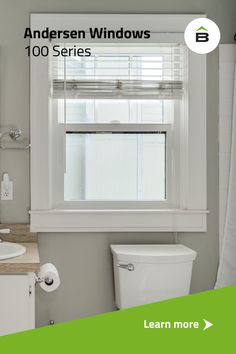 a white toilet sitting under a window next to a sink