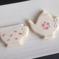 two decorated cookies sitting next to each other on a white tablecloth with pink flowers