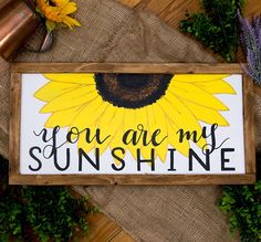 a wooden sign that says, you are my sunshinene on it next to some flowers