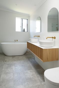 a bathroom with two sinks and a bathtub in the middle of it, along with a large mirror on the wall