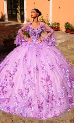 Look regal and radiant in this lilac purple ball gown quinceañera dress. The beautiful pastel hue perfectly complements the 3-D flowers that pop against the embroidered lace corset bodice and poofy glitter tulle skirt. For an extra princess vibe, this purple quince dress has a sheer bolero jacket with matching embellishments and dainty bell sleeves. Step into your milestone celebration in style when you wear this lilac purple quinceañera dress. Purple Quince Dress, Purple Ball Gown, Quince Stuff, Princess Vibe, Purple Quinceanera Dresses, Purple Quince, Quince Dress, Flower Embellishments, Sleek Dress