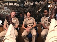 three people in uniform sitting at a bar with their feet propped up on the counter