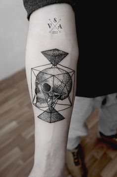 a man's arm with a skull and diamond tattoo on it, in black and white