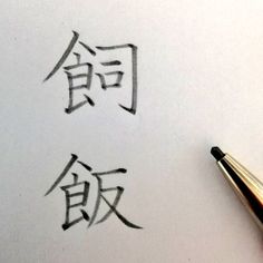 two chinese characters are drawn on paper with a fountain pen in the foreground and an eraser next to them