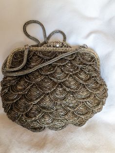 Small purse very refined, vintage spirit and Art Deco style Dimensions 20 x 17 x 7 cm It is entirely beaded by hand, on each side, with rock beads that form mobile scales. It is flexible, lined with fuchsia satin, with a small inner pocket. Its clasp, inspired by an ancient reticle, adds to its refinement. It is made of solid brass in aged silver color, of beautiful craftsmanship (as well as its shoulder strap). It can be worn both in the evening and during the day: it all depends on the outfit Vintage Evening Bags, Aged Bronze, Small Purse, Art Deco Style, Deco Style, Art Deco Fashion, Cross Body Handbags, Evening Bags, Solid Brass