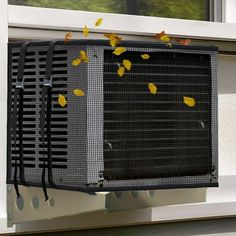 an air conditioner sitting on the side of a window sill covered in yellow leaves