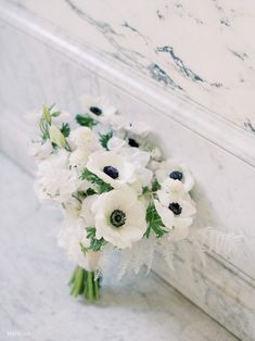 a bouquet of white flowers sitting on top of a marble counter