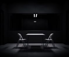 two white chairs sitting at a table in the middle of a dark room with light coming from above