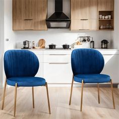 two blue chairs sitting in front of a stove top oven and counter with wooden cabinets