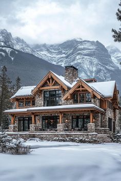 a large stone and wood house in the snow with mountains in the backgroud