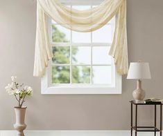 a living room scene with focus on the window and flowers in vases next to it