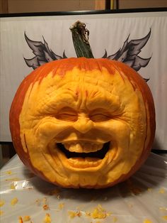 a pumpkin carved to look like an angry face with wings on it's head