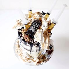 a cake decorated with liquor bottles and nuts on a white tablecloth covered plate in front of a white background