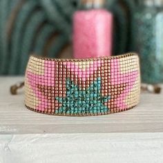 a pink and blue beaded bracelet sitting on top of a table next to a candle