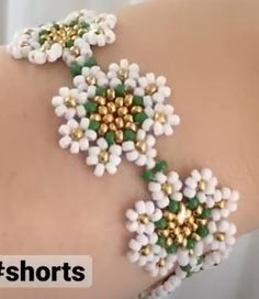 a woman's arm with white and green beads on it