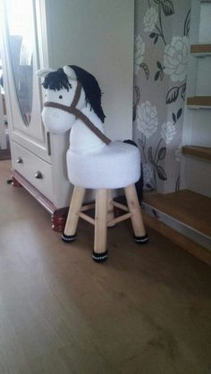 a white rocking horse sitting on top of a wooden floor next to a dresser and mirror