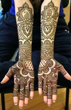 two hands with henna tattoos on them, one is showing the intricate pattern and the other