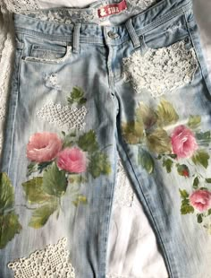 a pair of jeans with pink roses on them and lace trimming around the bottom