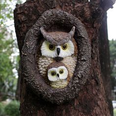 an owl and her baby are in a hollow on a tree trunk with their faces carved into the bark