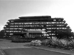 the building has many windows and plants in front of it