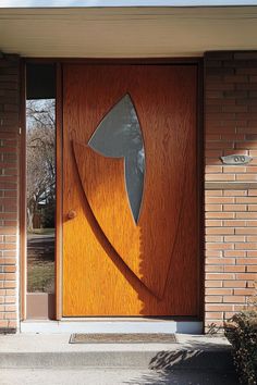 a wooden door with an abstract design on the side and brick building in the background