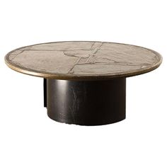 a round table with an artistic design on it's top and black base, against a white background