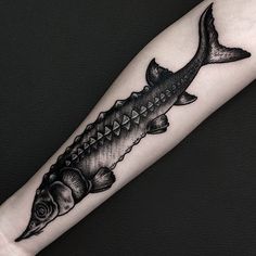 a fish tattoo on the arm with an arrow in it's tail and some other things