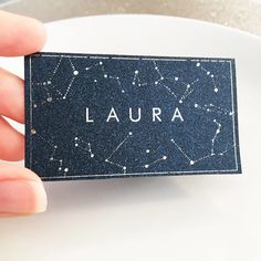 a hand holding a business card with the word laura written in white on it