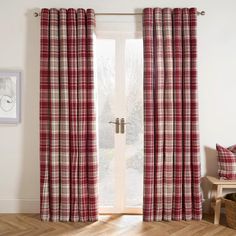 a red and white checkered curtain hanging in front of a window with wooden floors