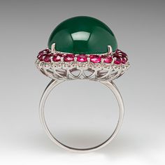 This elegant cocktail ring is centered with one (1) oval cabochon cut natural jadeite jade set with four-prongs and bordered with twenty-two (22) shared prong set, round mixed cut natural pink sapphires and eighty-eight (88) prong set, round brilliant cut natural diamonds. The ring measures 24.7mm at the top, rises 14.2mm above the finger, tapering to 1.8mm wide and 0.7mm thick at the base of the shank. One of the sapphire accents is lightly chipped and unnoticeable without magnification. The 18 Fine Jewelry Green Cabochons For Formal Occasions, Green Gemstone Cabochons For Formal Use, Green Cabochons For Formal Fine Jewelry, Elegant Green Gemstone Cabochons, Elegant Green Cabochons For Formal Occasion, Elegant Emerald Jade Ring With Cabochon, Formal Cabochon Chrysoprase Jewelry, Elegant Oval Chrysoprase Rings, Green Gemstone Cabochons Fine Jewelry