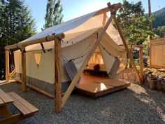 a tent set up in the middle of a gravel area with wooden benches around it