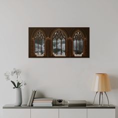 three windows in a white room with flowers and books on the table next to them