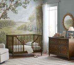 a baby's room with a crib, dresser and wall mural in the background