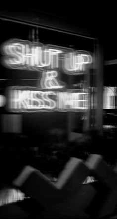 the words shut up and kiss me are lit up in front of a black background