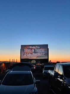 an outdoor drive - in theatre is lit up at dusk with cars parked on the lot