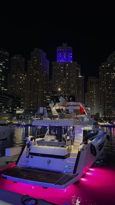 a boat that is sitting in the water near some buildings with lights on it at night