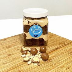 a jar filled with chocolate covered cookies on top of a wooden table next to nuts