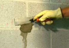 a person is using a trowel to fix a hole in the wall