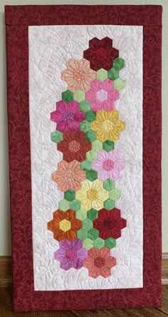 a quilted wall hanging with many different flowers on it's sides and the bottom half