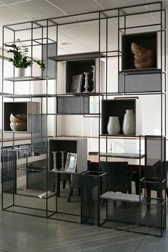 an office with shelves and chairs in the center, filled with vases on each shelf