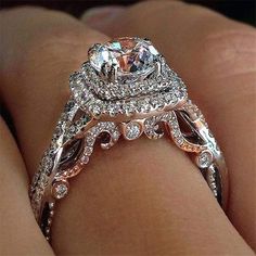 a woman's hand with an engagement ring on her left side and the center stone is surrounded by diamonds