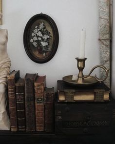 there is a statue next to some books and a candle