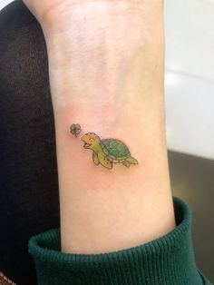 a small turtle tattoo on the wrist with a clover in it's tail,