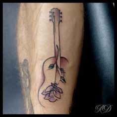 a tattoo on the leg of a man with a guitar and flower in it's center