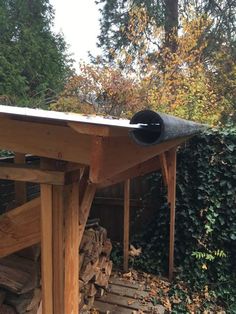 a pile of wood sitting next to a wooden structure with a pipe sticking out of it