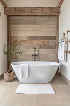 a white bath tub sitting in a bathroom next to a towel rack and wooden wall